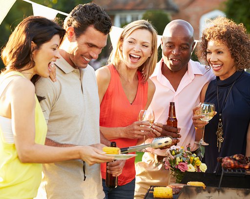 mature friends enjoying outdoor summer barbeque in garden